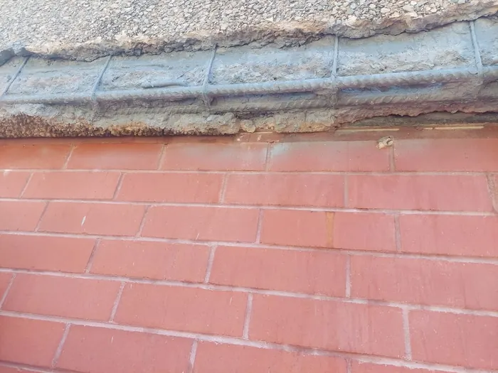 Spalled concrete cut back to expose the reinforcement, treated with rust-inhibiting primer