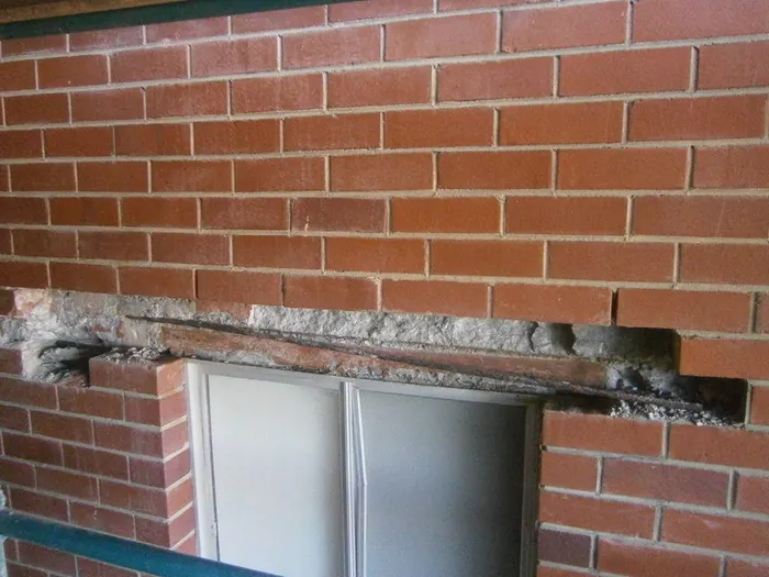 Brickwork removed to expose a failed lintel above a window